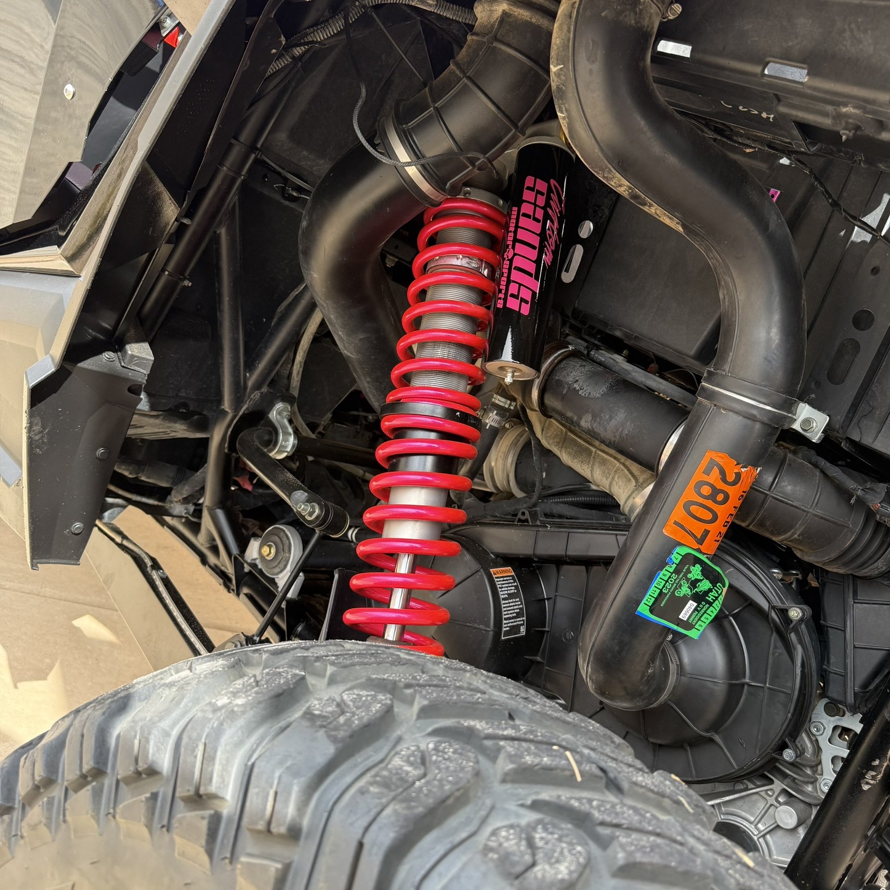 A row of golf clubs on a golf cart with black seats, with the word 'BADK1T' spelled out on the clubs, outdoors under a partly cloudy sky.