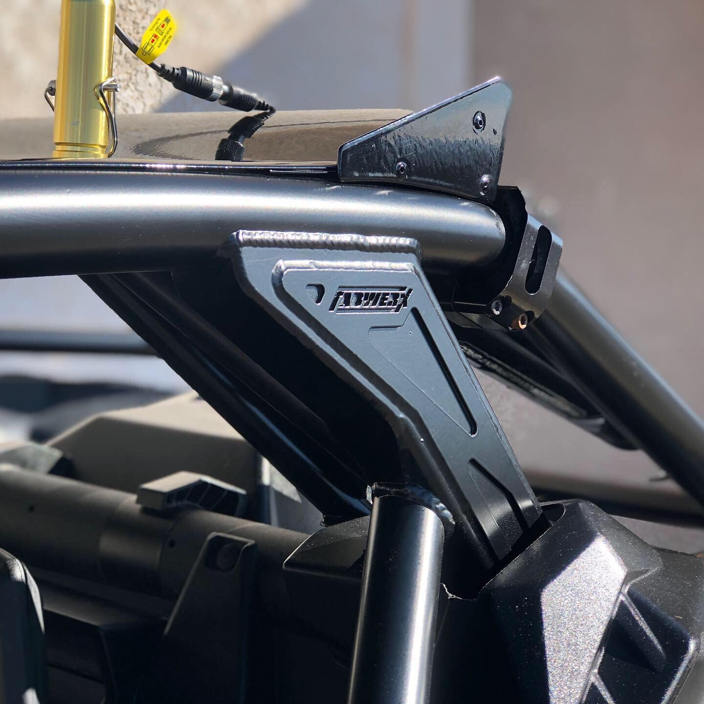 Close-up of a metallic racing simulator cockpit frame with a black and silver front support structure and a yellow handle in the background.