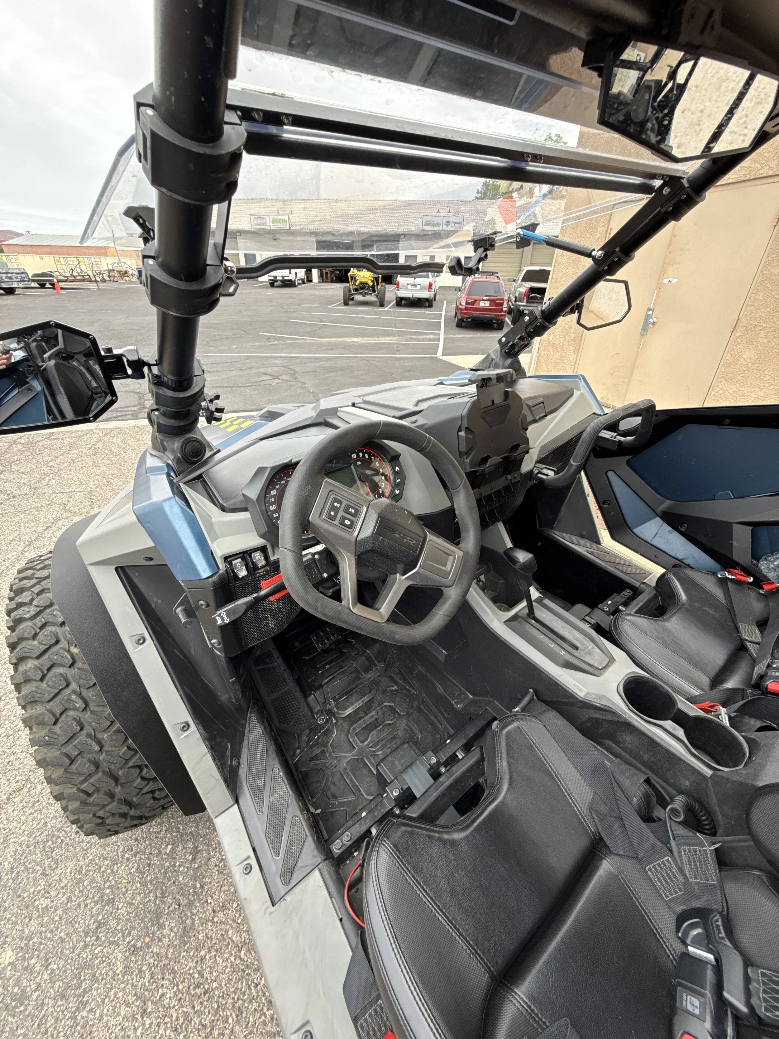 Close-up of a vehicle's rear engine compartment revealing a black BRP logo, shock absorbers, and mechanical components.