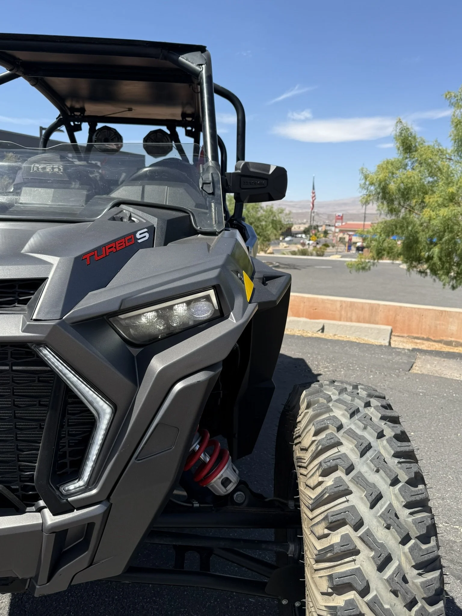 Close-up of a metallic racing simulator cockpit frame with a black and silver front support structure and a yellow handle in the background.