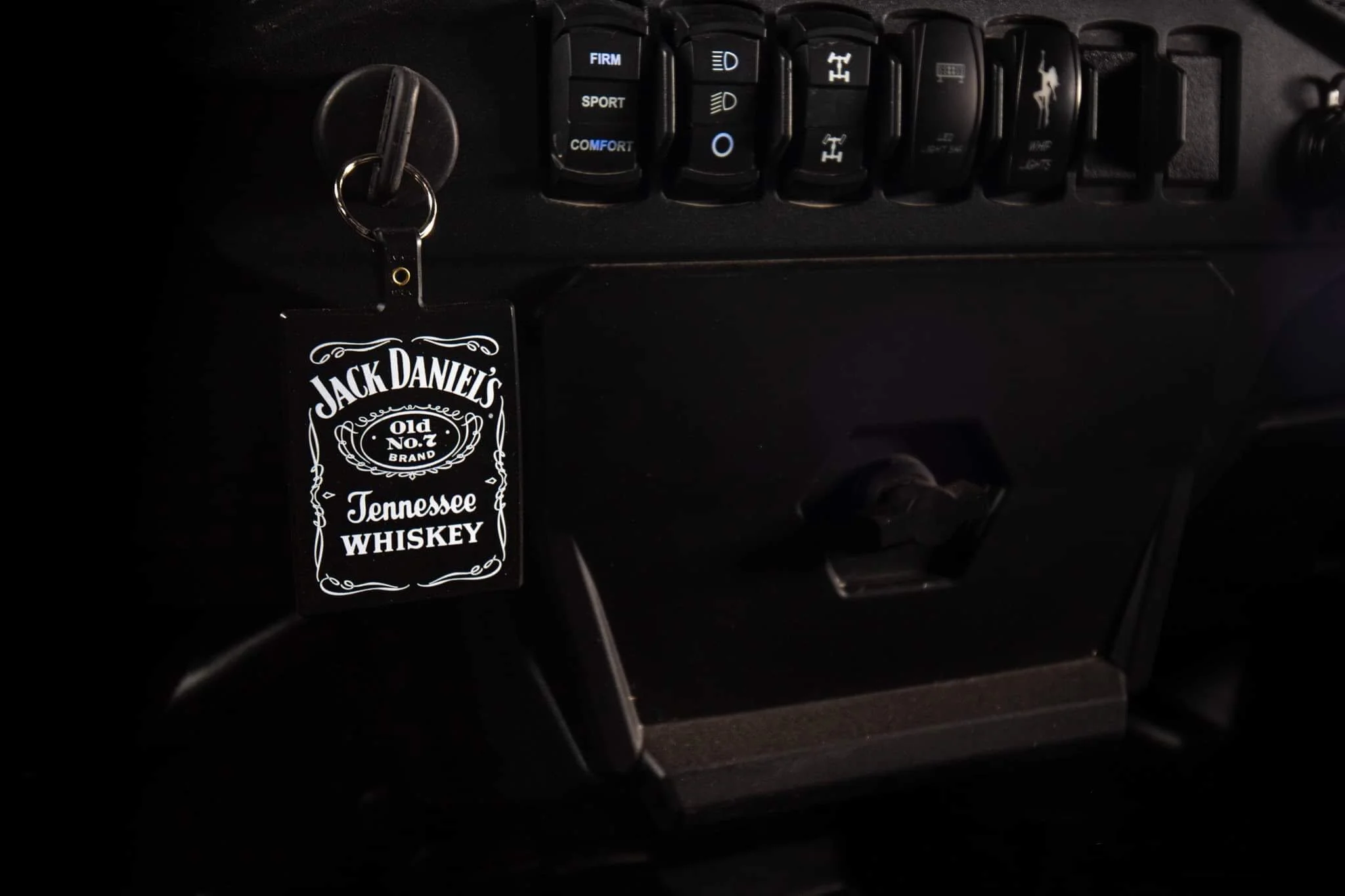 Keychain with Jack Daniel's Tennessee Whiskey label hanging from vehicle ignition switch.