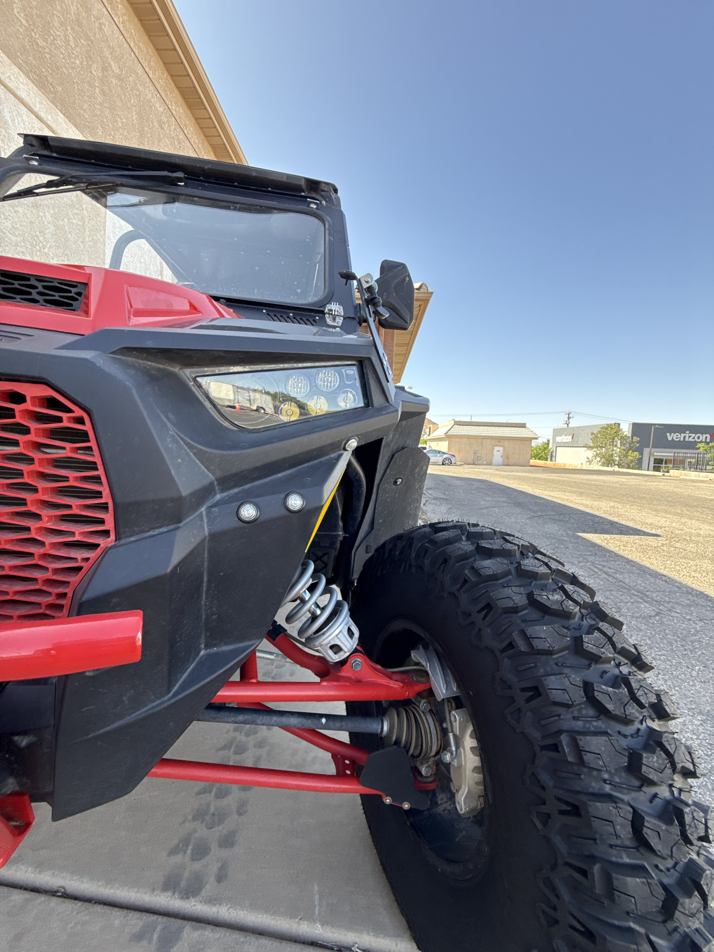 Close-up of a metallic racing simulator cockpit frame with a black and silver front support structure and a yellow handle in the background.