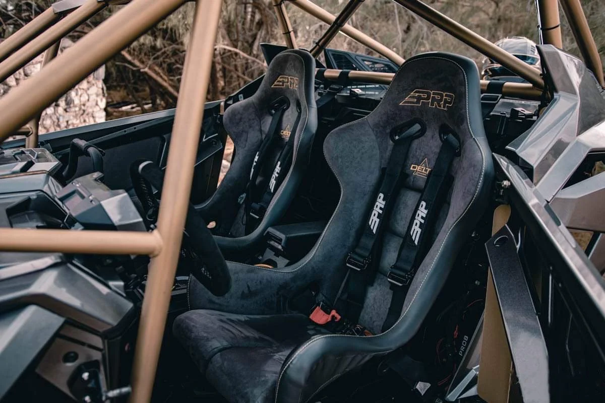 Interior of a race car with two racing seats, visible dashboard, and a roll cage.