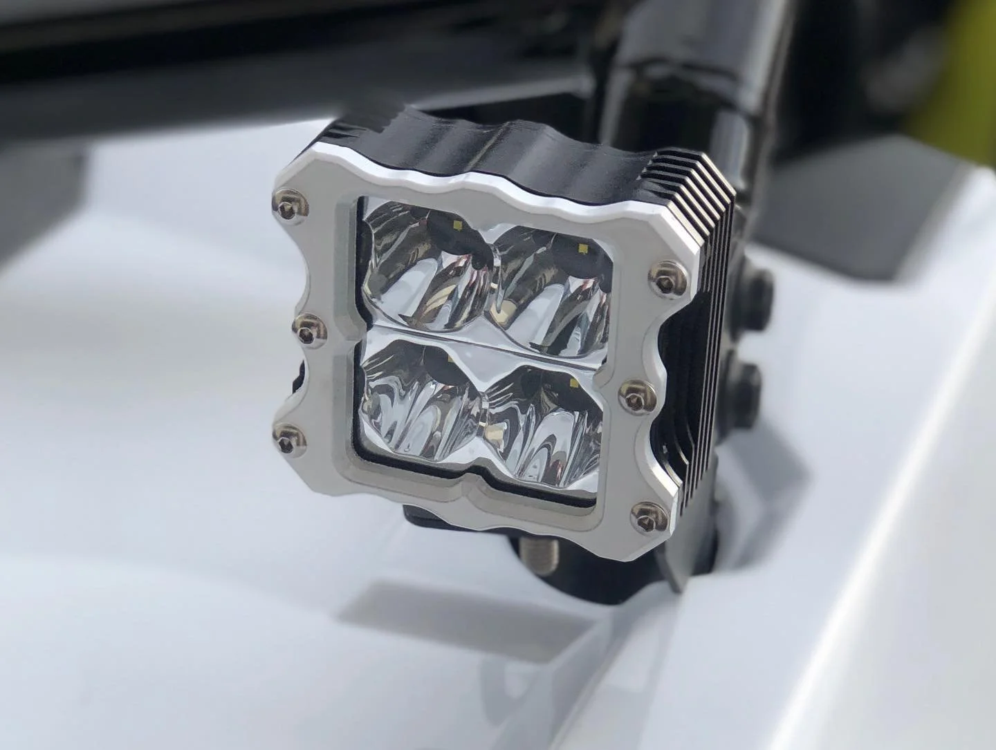 Close-up of a high-power LED light with four individual LED bulbs housed in a metallic square frame, mounted on a black heat sink.