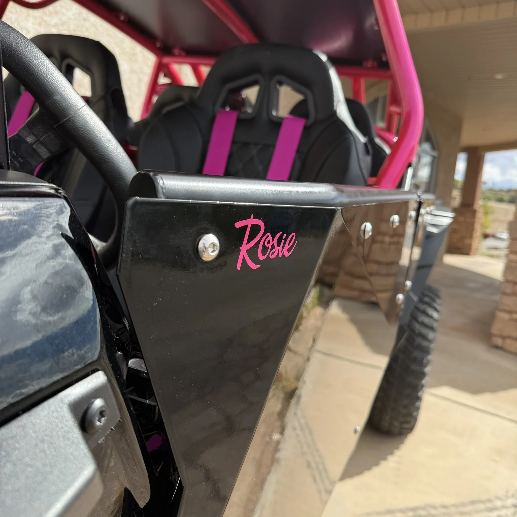 An off-road dune buggy driving on a dirt road during sunset in a desert landscape.