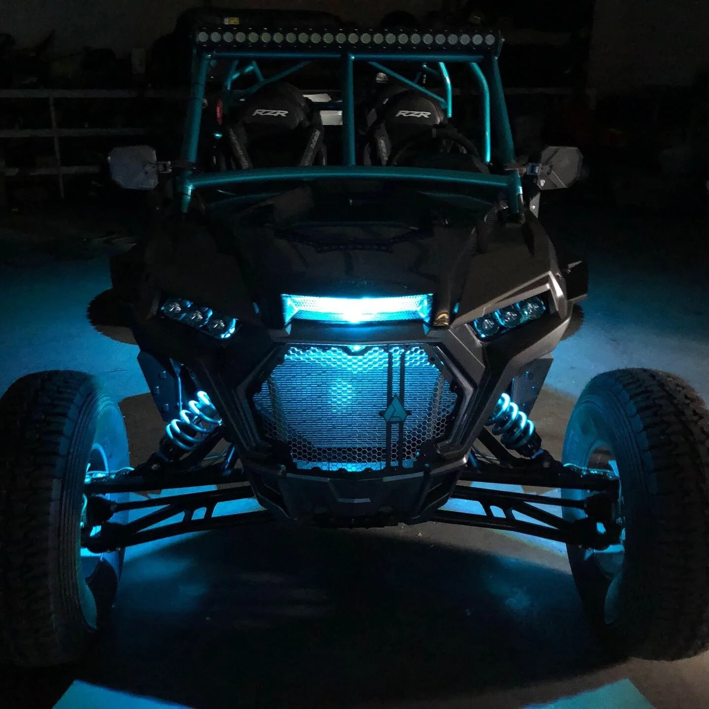 Black off-road vehicle with glowing blue lights, large tires, and exposed suspension.