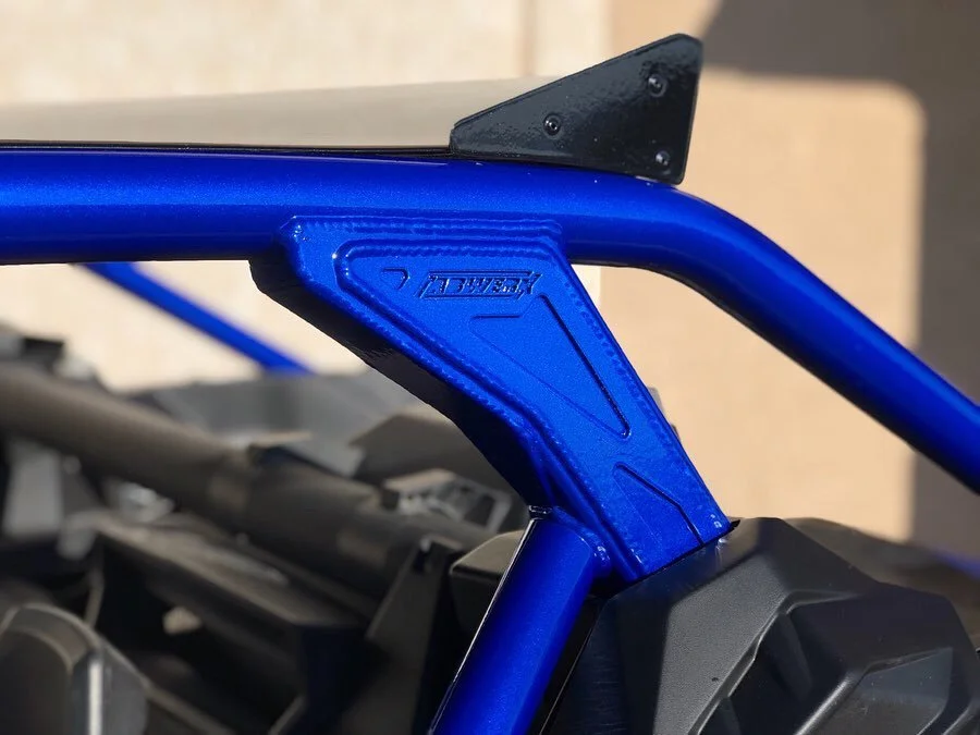 Close-up of a blue roll cage or protective frame on a vehicle, with a black mounting bracket attached.