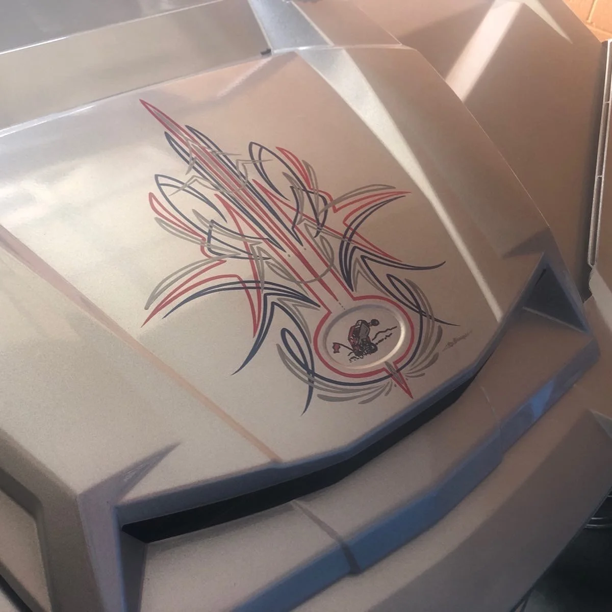 Metal surface with a colorful flame-themed tattoo-style design and a small circular emblem featuring a person holding a gun.