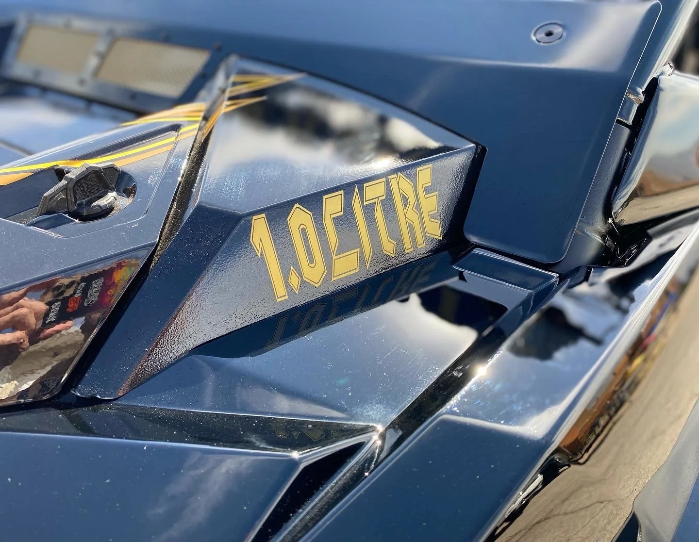 Close-up of a metallic blue vehicle with the text '1.0 CITRE' in yellow on the front panel.