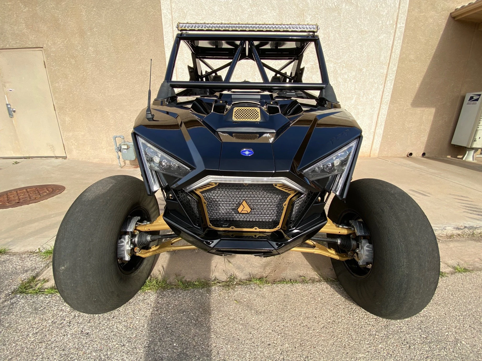 A black and gold off-road vehicle with large tires, modern headlight design, and a visible roll cage.