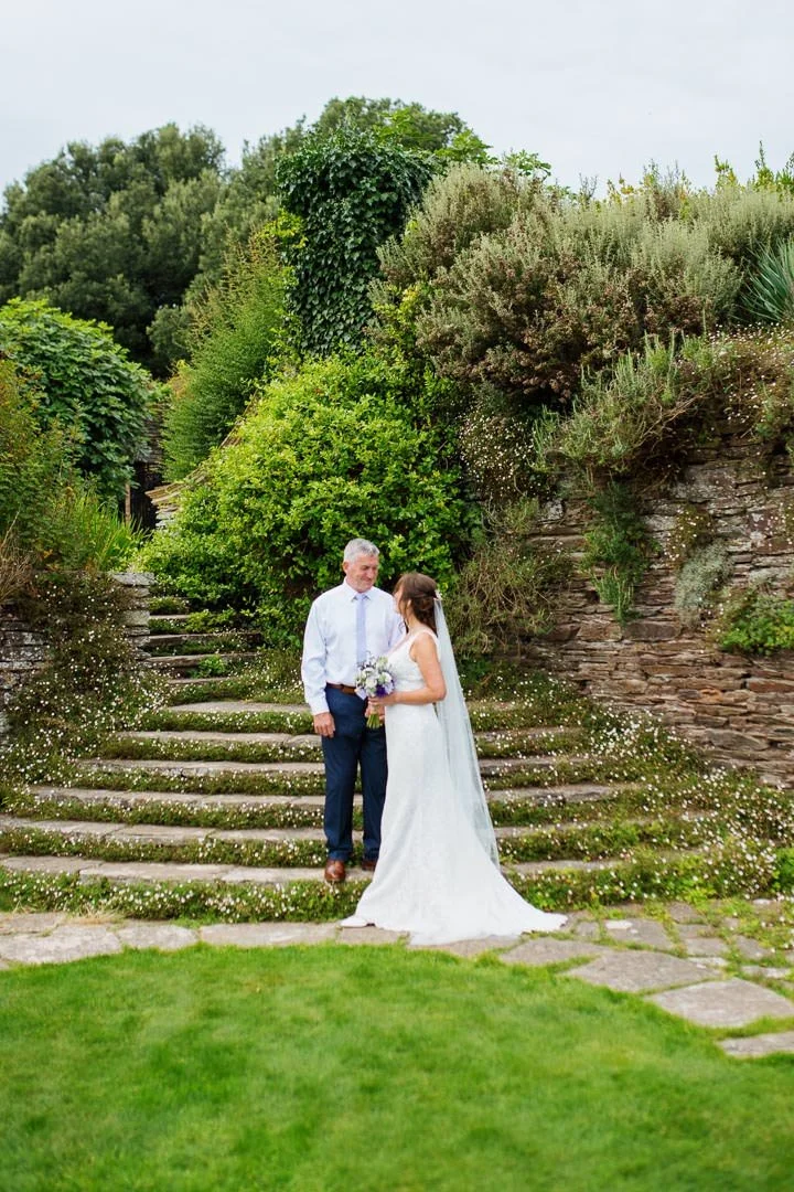 wedding could stood on steps under large tress kissing. Hestercombe House