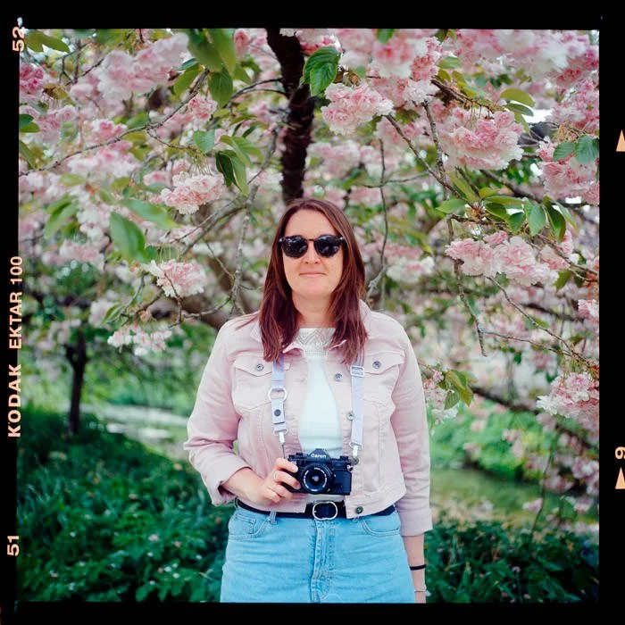 girl waring pink jacket holding film camera under blossom tree, Kodak ektar 100