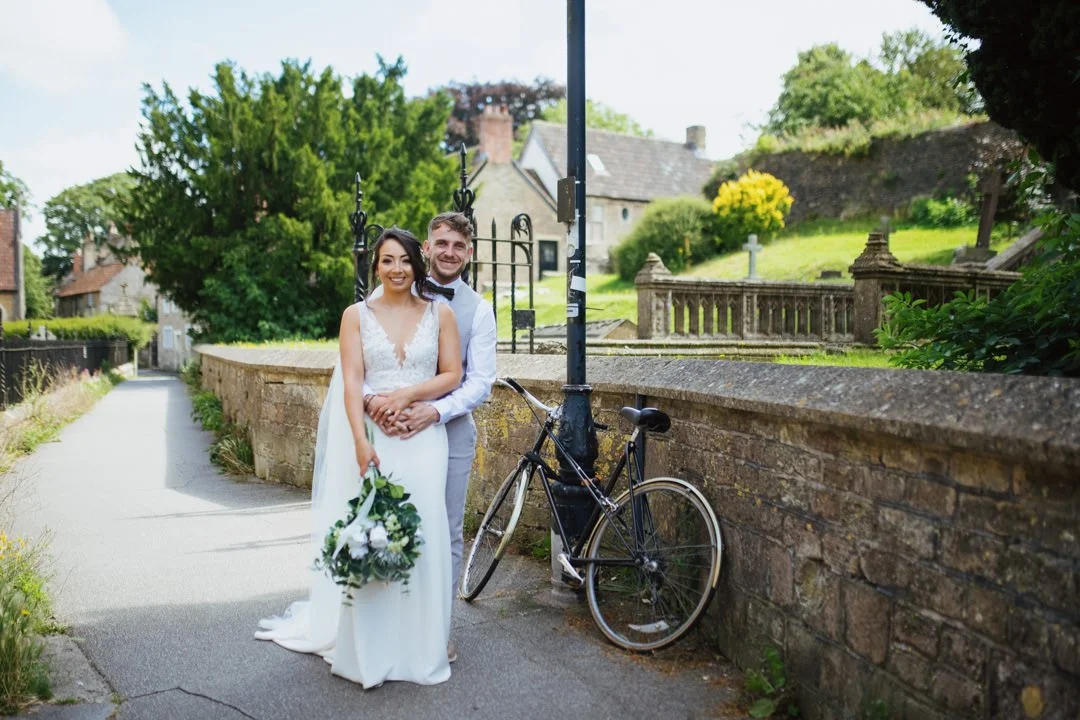 bride and groom stood in street outside church. they are holding hands and smiling