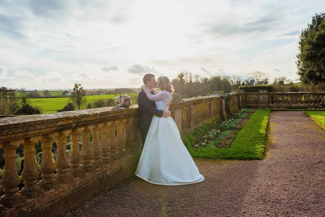 wedding couple kissing stood in garden with flowers during sunset, Hestercombe House Somerset