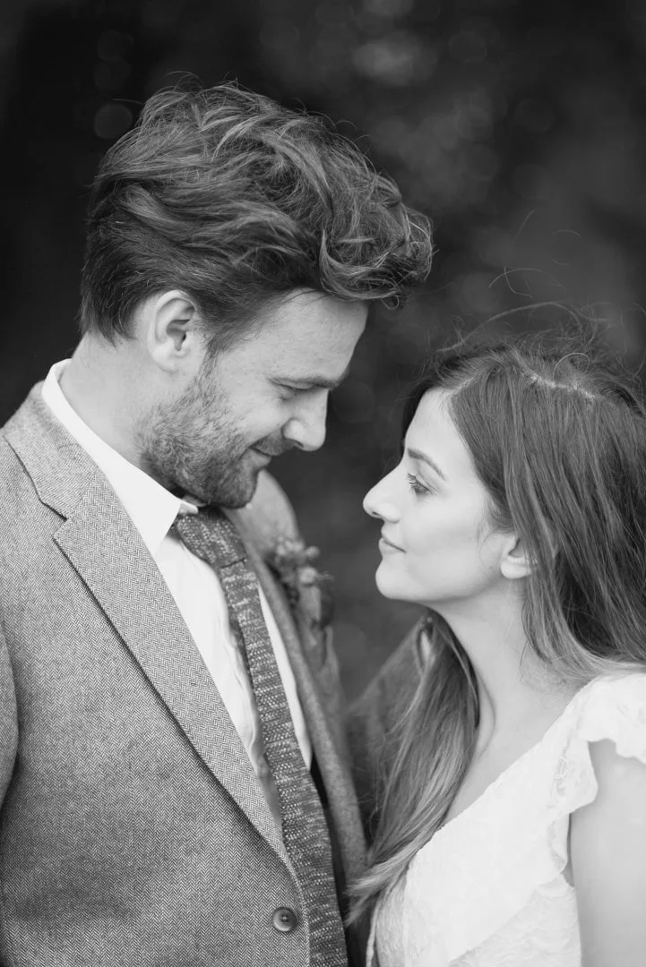 black and white photo of bride and groom stood on beach