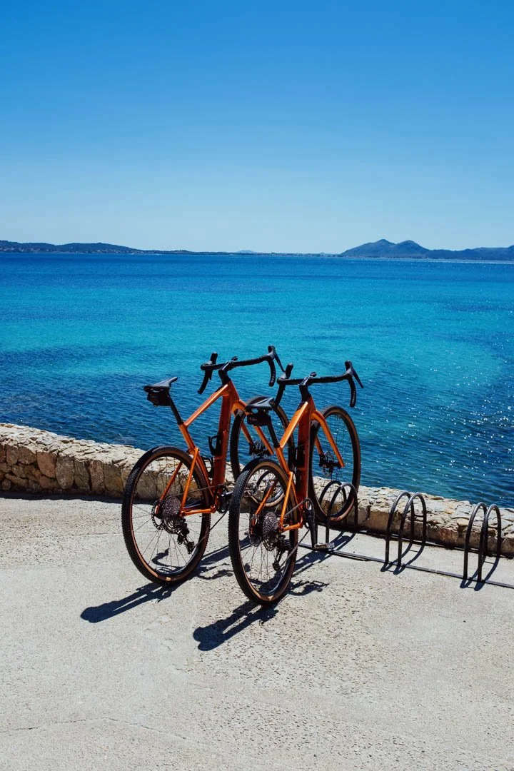 two red road bikes parked on beach, formentor majorca