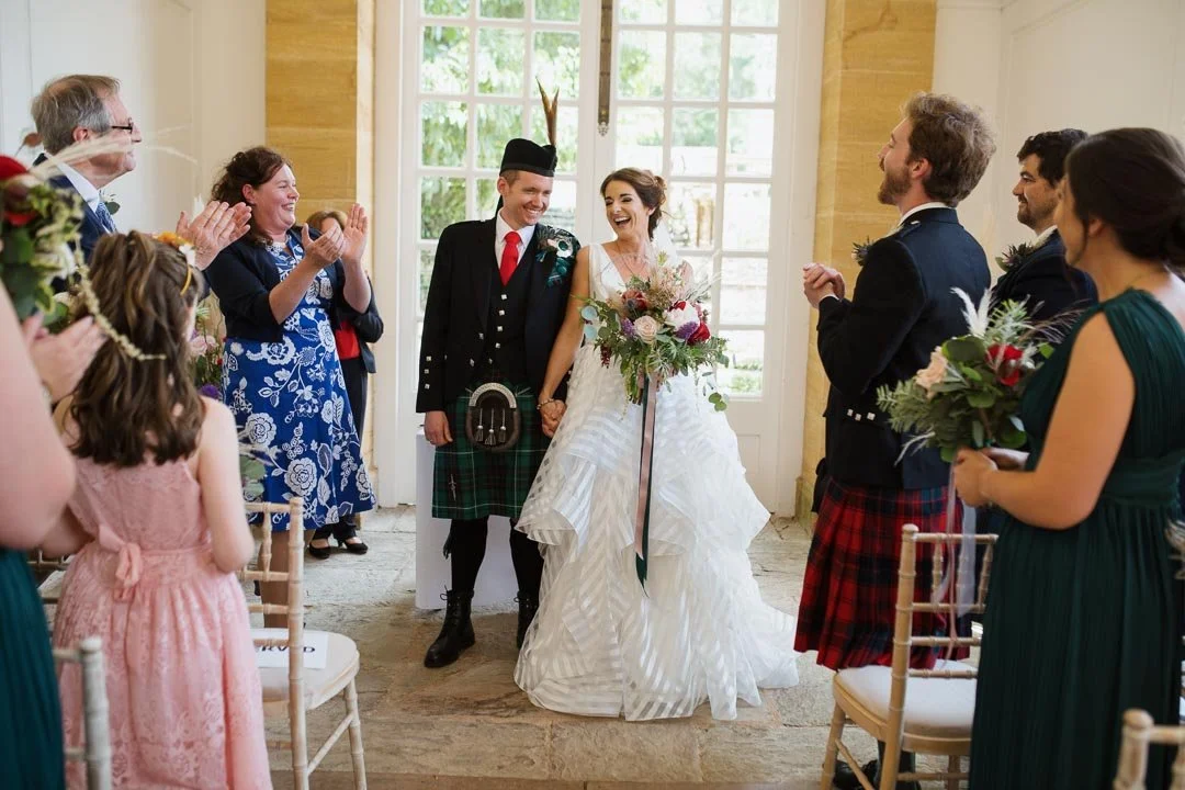 wedding couple holding flowers cheering with large crowd, Hestercombe House Somerset