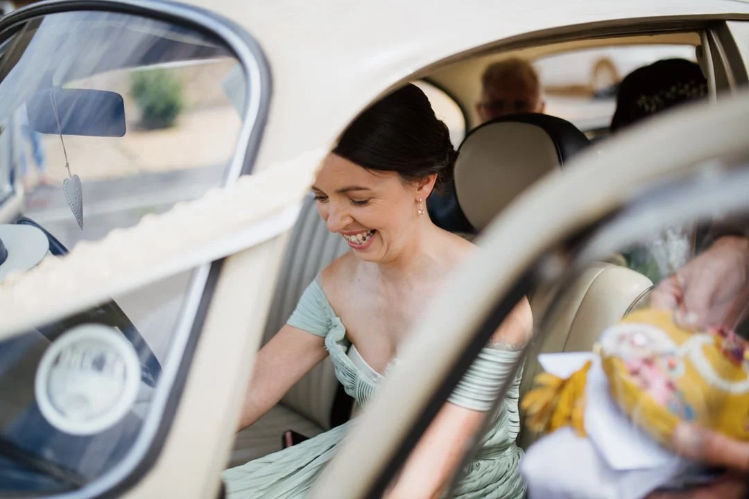 bridesmaid waring green dress sat in front seat of vw beetle