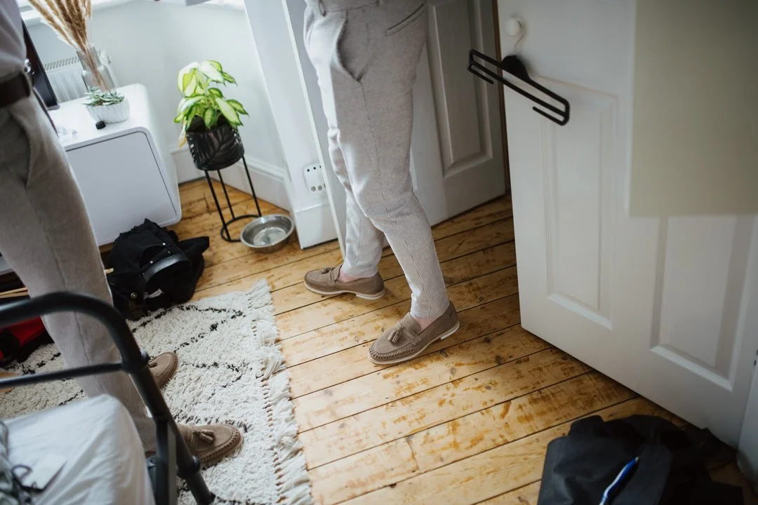 man waring grey trousers and brown plum sole shoes standin on wooden floor