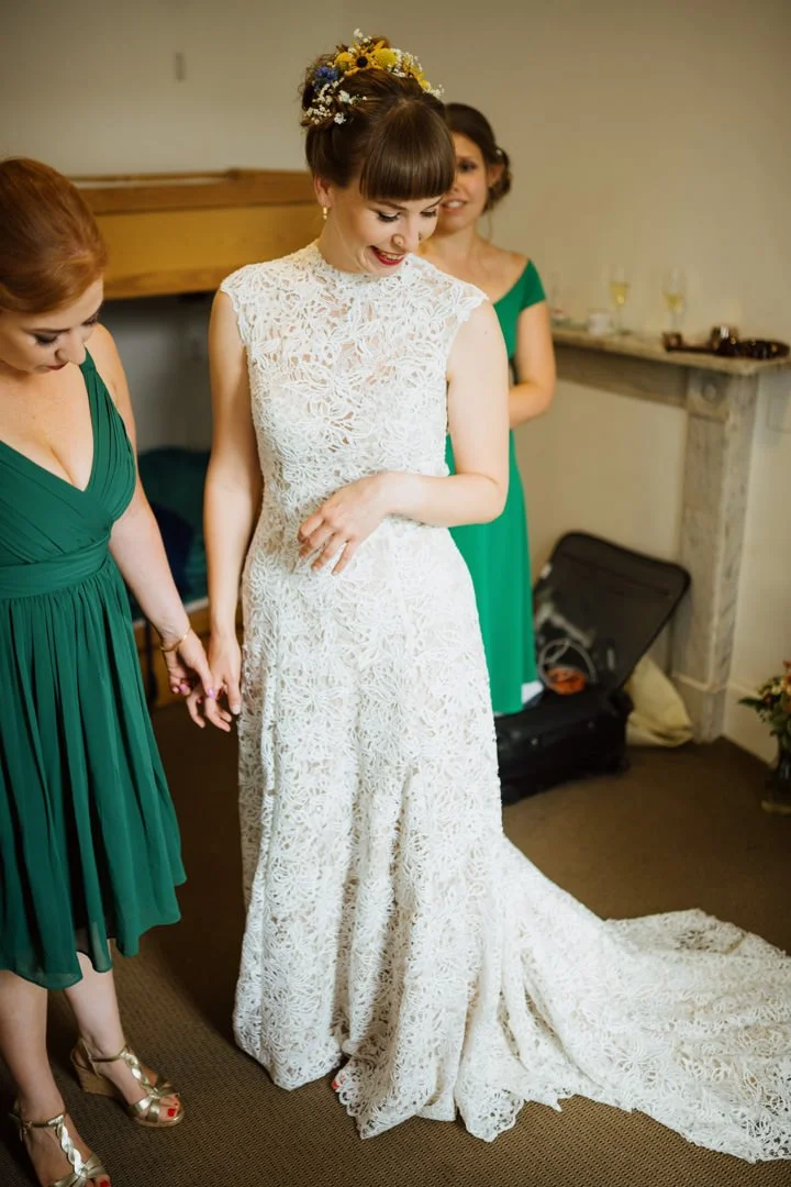 bride stood in white dress smiling in bedroom