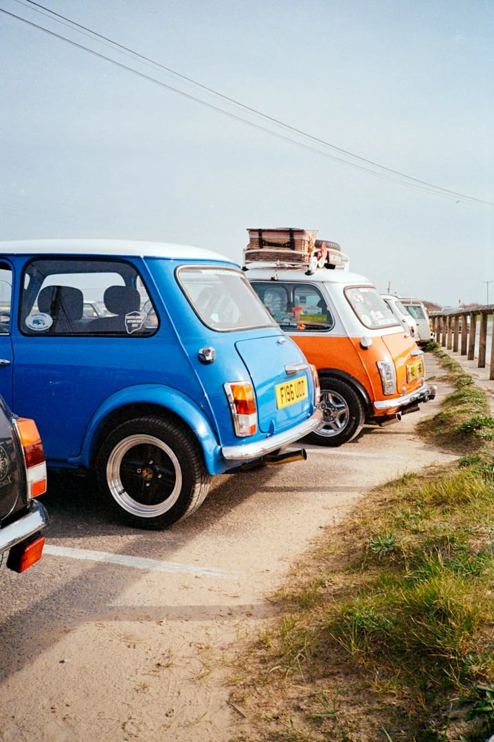 classic mini cars parked in a line near wooden fence