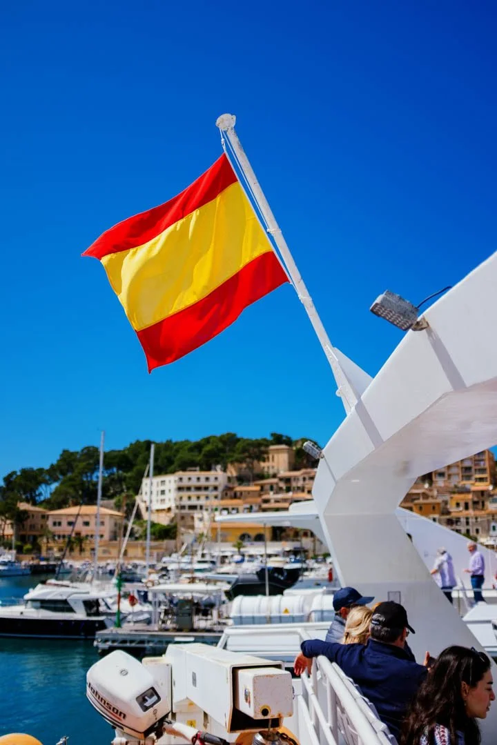 Spanish flag on the back of a yacht in harbour with blue ocean