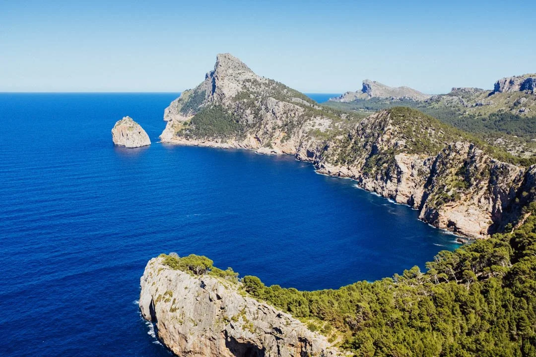 large rock formation with ocean below and trees on cliff top, formentor majorca