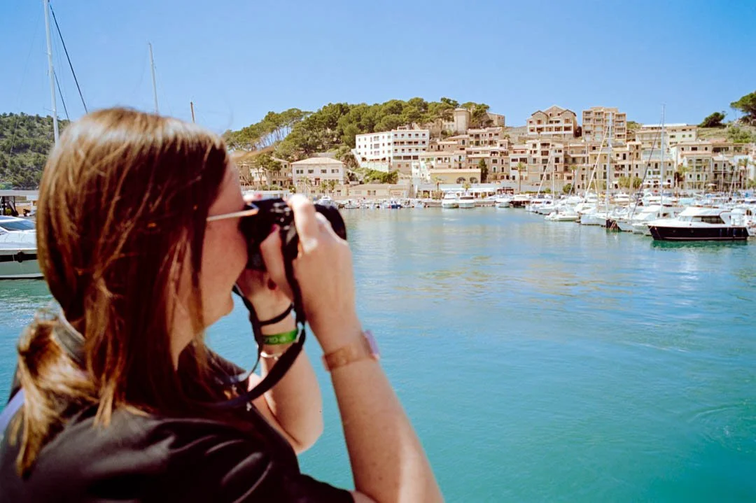 girl taking photo on a film slr from the back of a boat in port de sollar