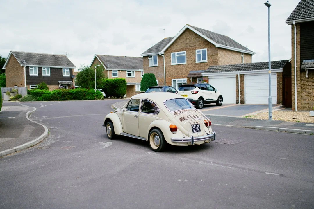 classic vw beetle car parked on road under grey skies.