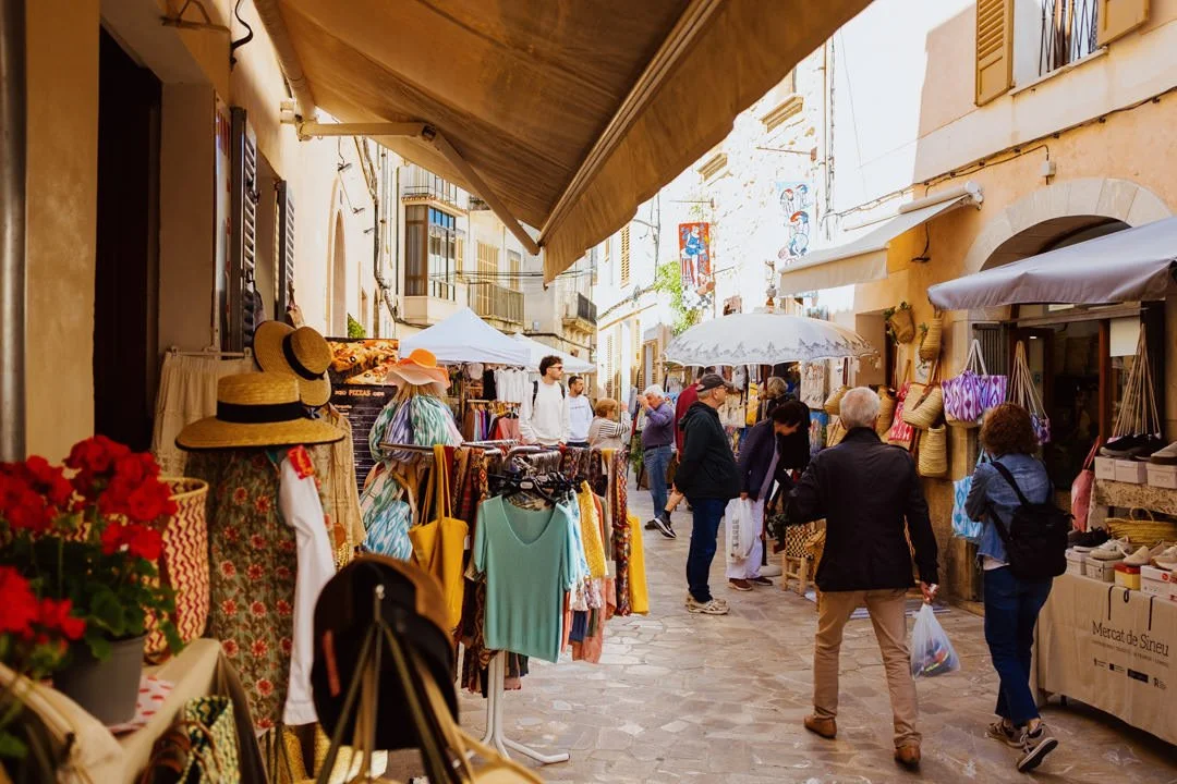Alcudia market with shops selling clothes in narrow street