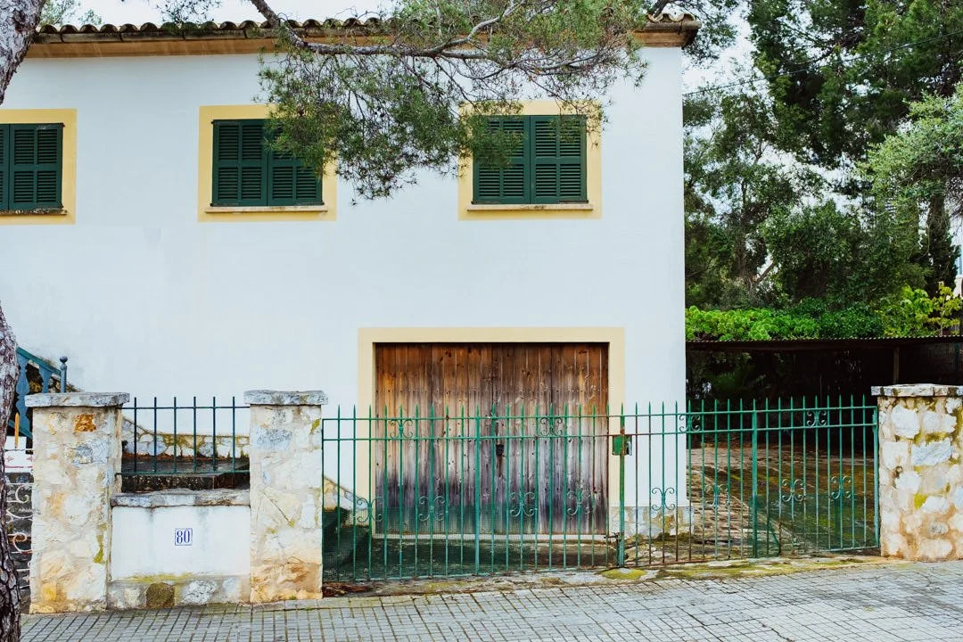 large white hose with wooden doors and green window covers