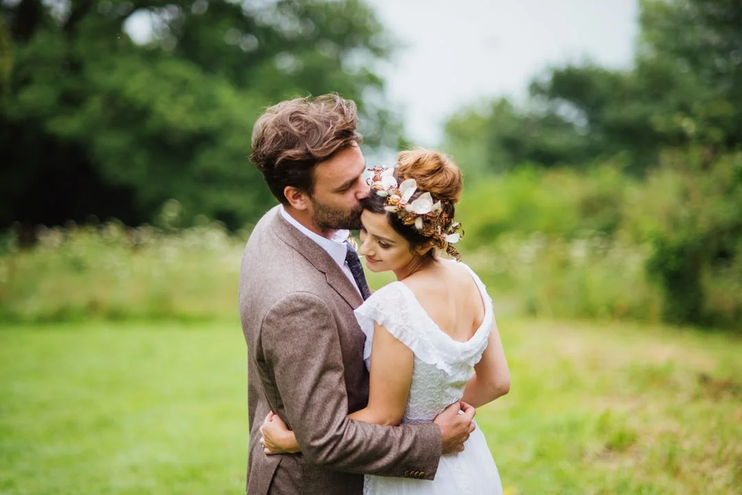 bride and groom stood in field embracing and smiling