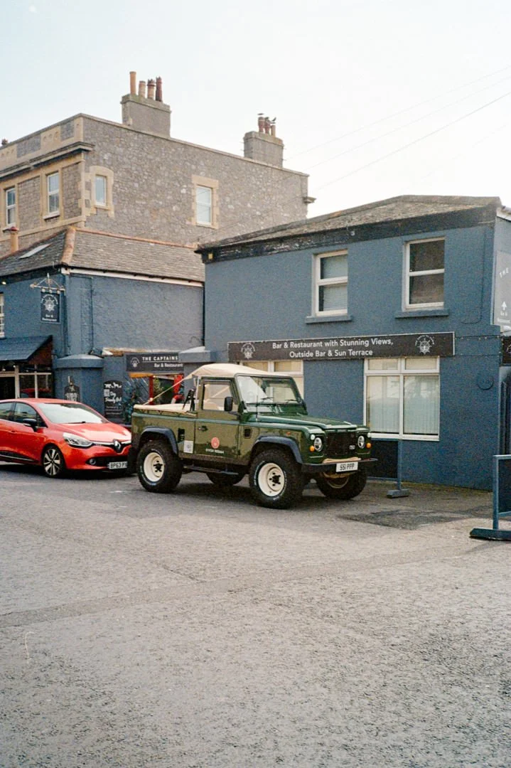 green land rover outside blue hotel.