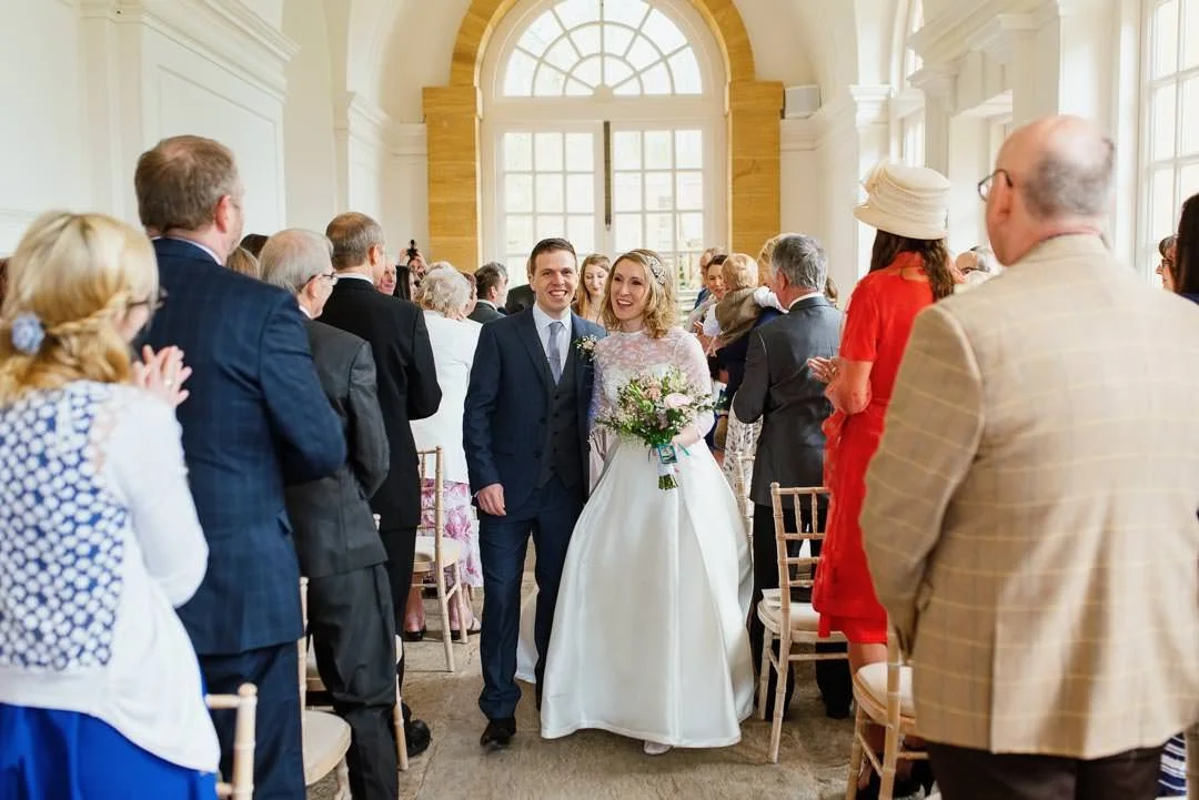 bride and groom walking holding hands in large orangery, Hestercombe House