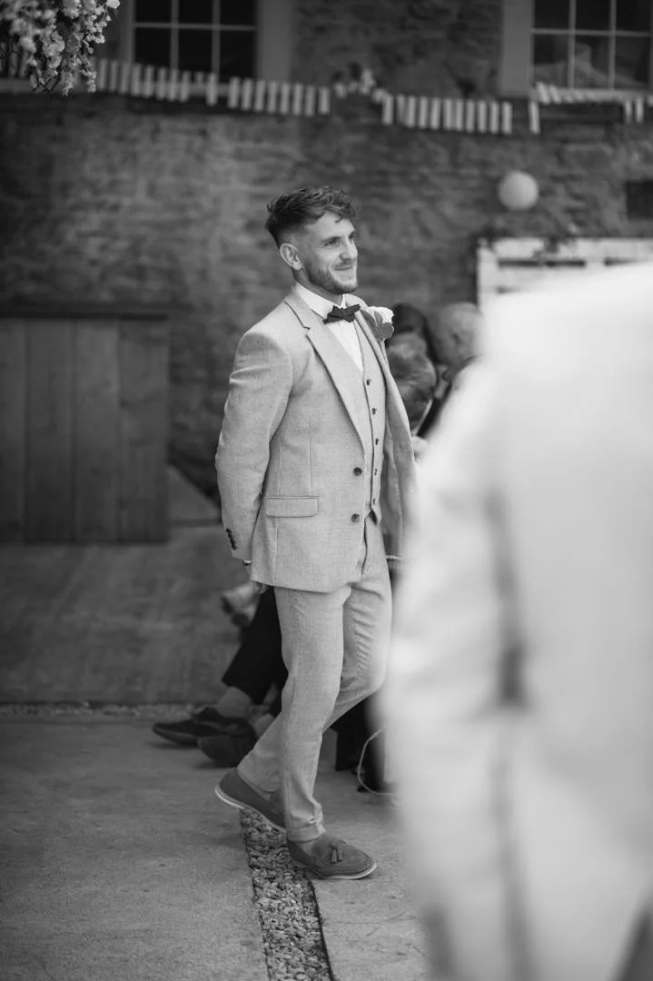 black and white photo of groom waring a grey suit and leather shoes