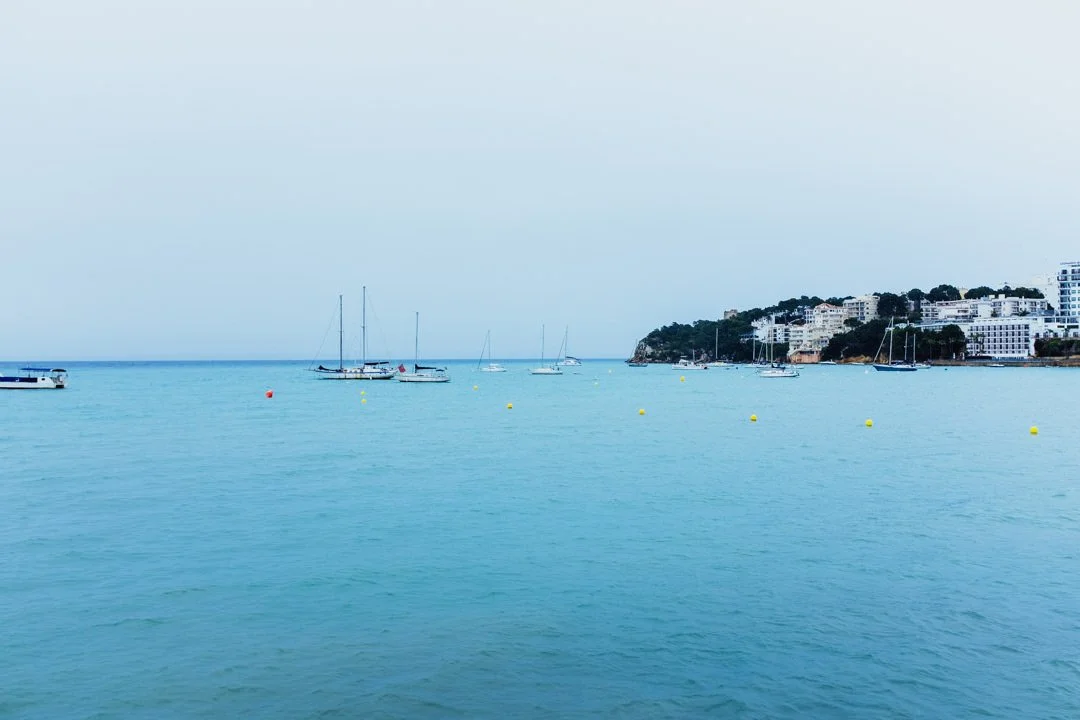 Palma Nova harbour with blue water and boats under cloudy skies