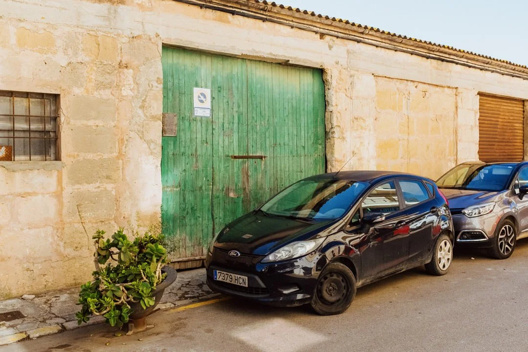 black ford car next to green wooden barn door under bright sun