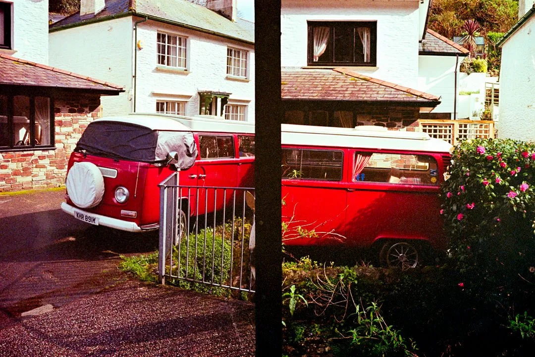 red vw camper van next to large rose bush
