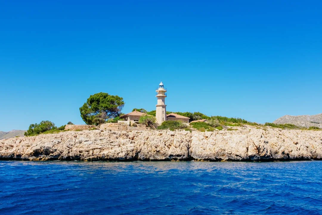 Orange lighthouse on rocks near ocean, Formentor Majorca