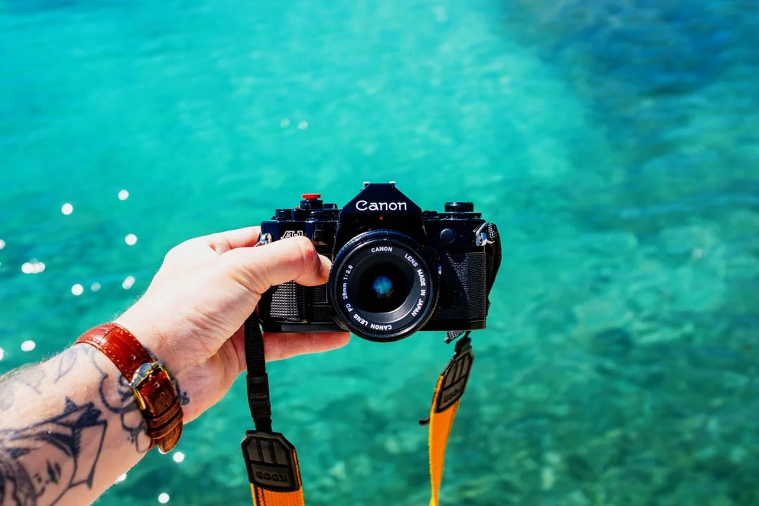 canon a1 film camera with blue ocean behind it