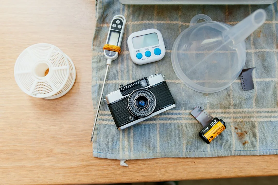 Olympus half frame camera next to film developing equipment