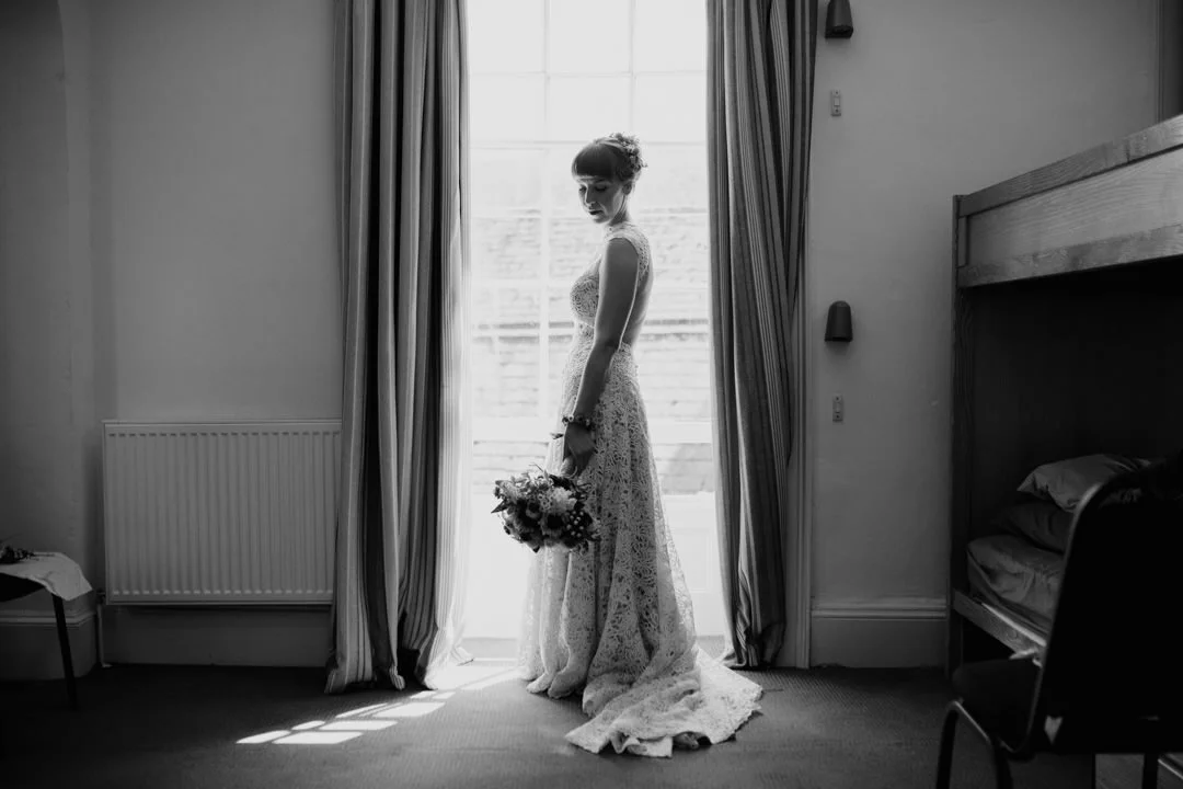 bride holding flowers stood infront of large window