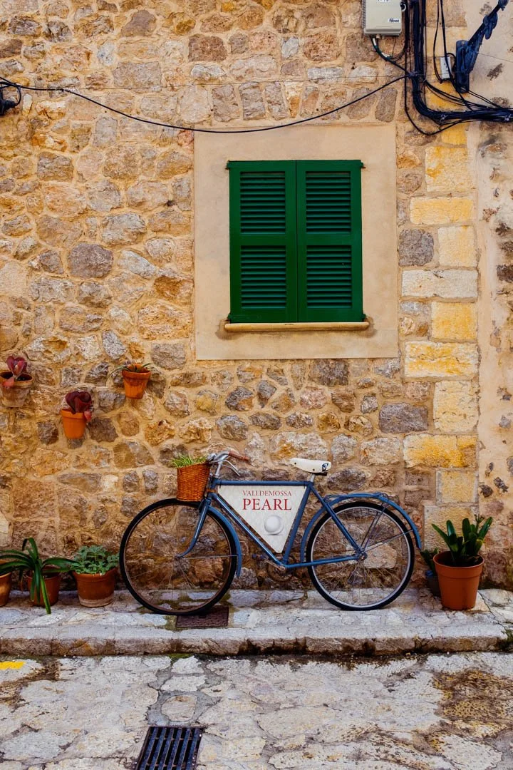 blue bicycle on street next to window in Valldemossa