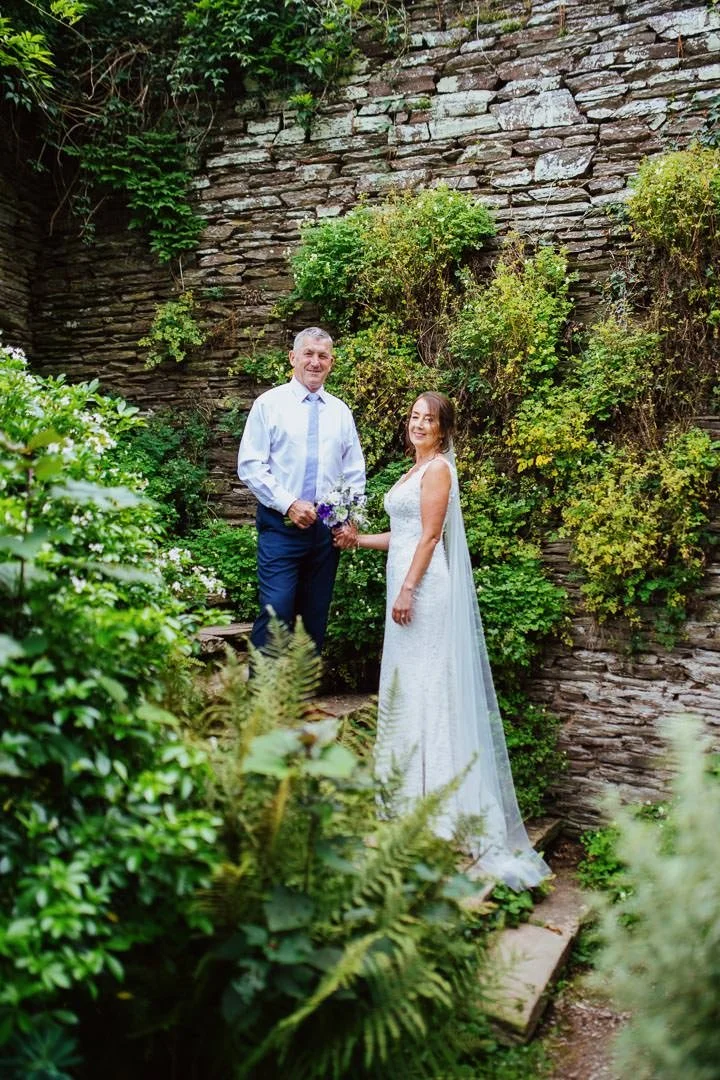 bride and groom stood on steps surrounded by flowers
