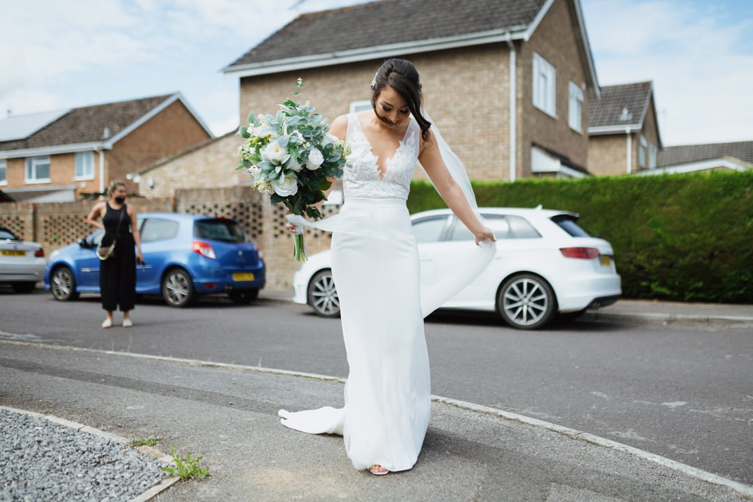 wedding bride walking in street holding white flowers