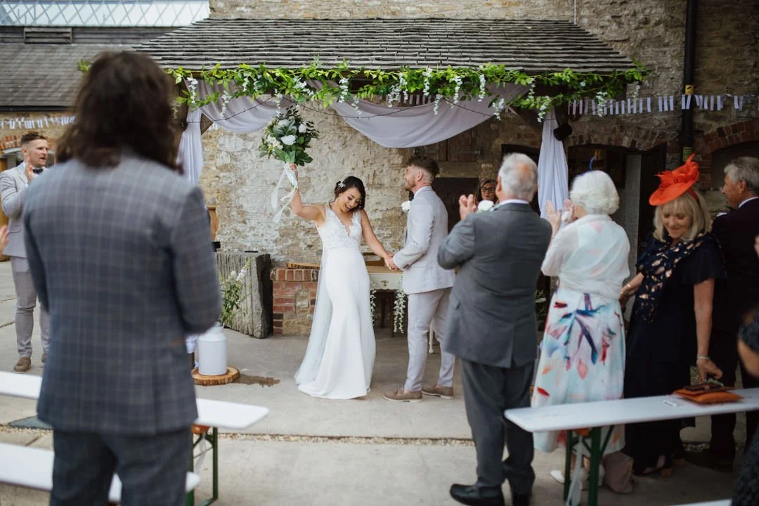 bride holding up flowers and cheering looking at large crowd
