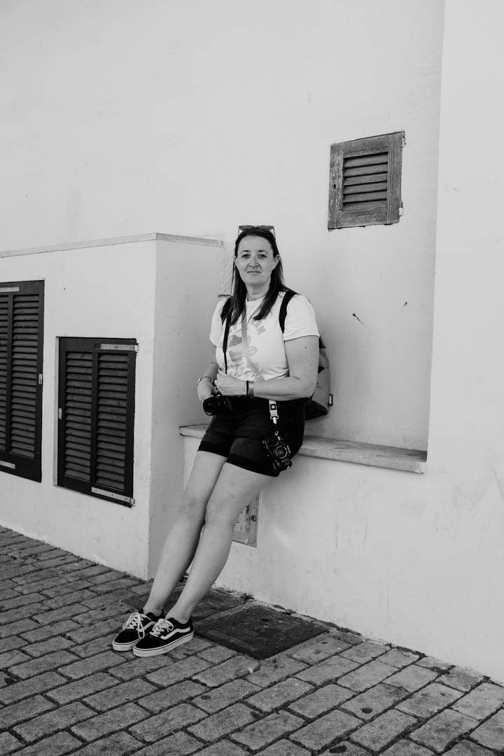 girl in white t shirt with vintage camera around her neck, she is waring vans shoes