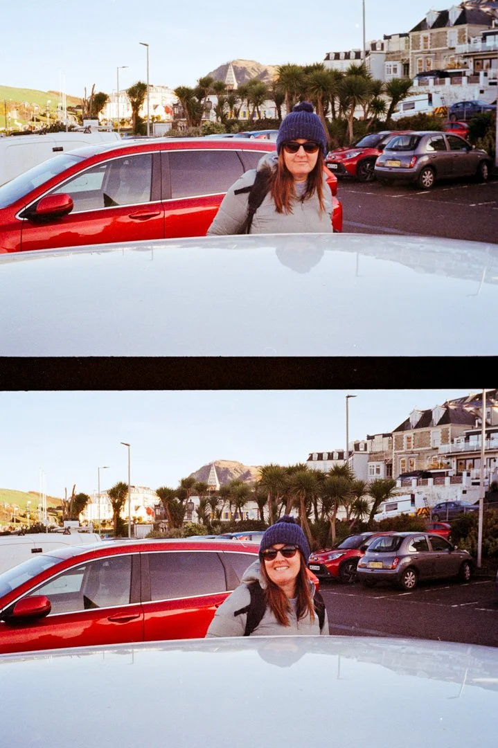 women with blue hat on stood next to red car