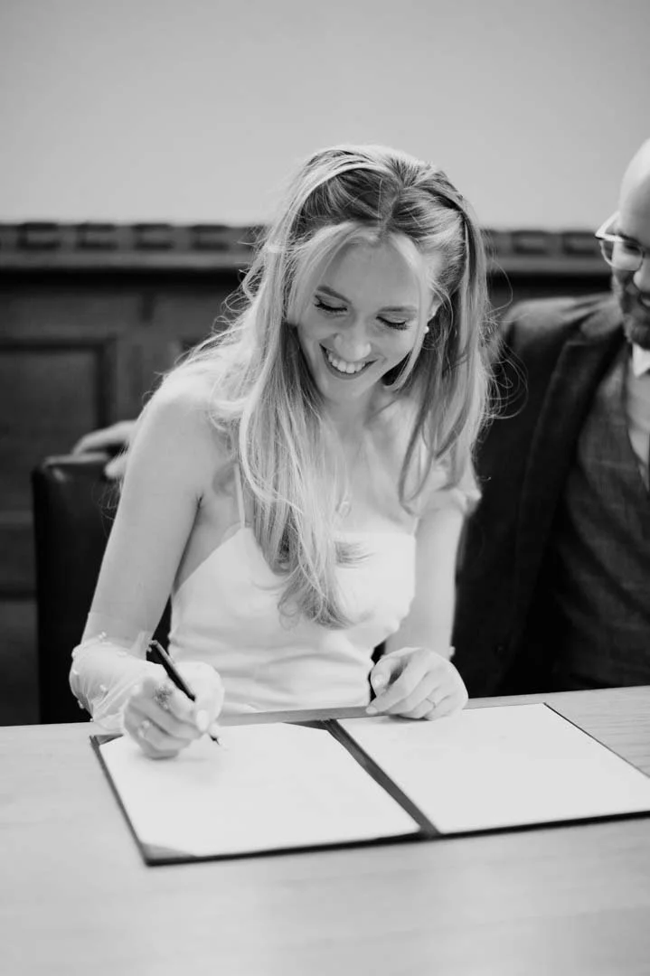 wedding bride signing register sat at large table