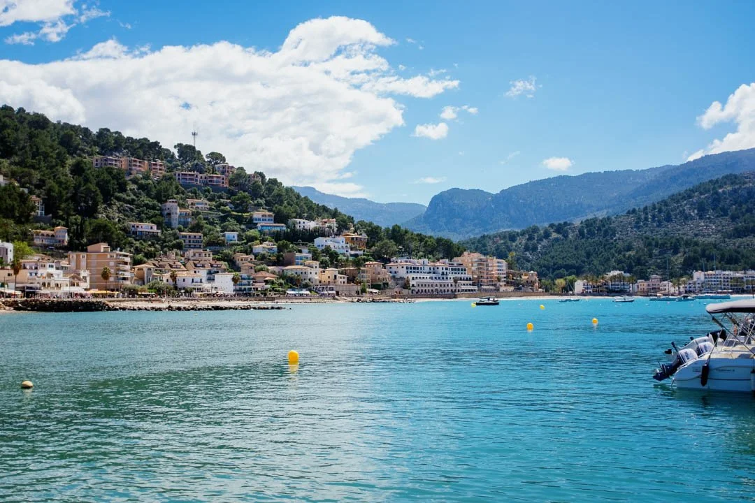 port de Sóller harbour with blue water. there are boats in the middle and mountains behind